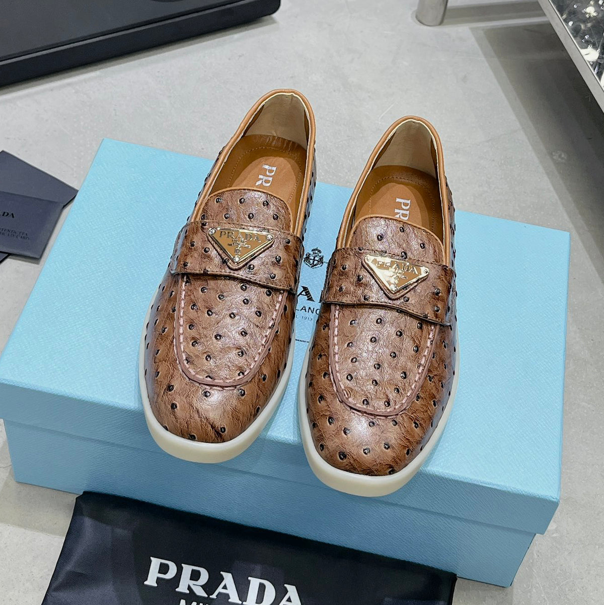 Ostrich Grain Metal Triangle Badge Slip-On Loafers S283422